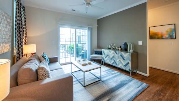 A living room with a brown couch and a glass coffee table. at Kensington Place Apartments, Woodbridge, Virginia