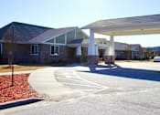 Thumbnail 2 of 8 - A white covered walkway leads to a building with a brick facade.