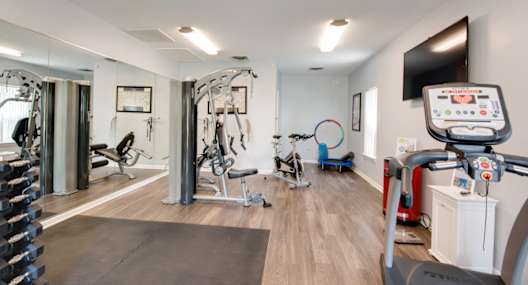 A gym with a variety of exercise equipment including treadmills, stationary bikes, and weight machines.