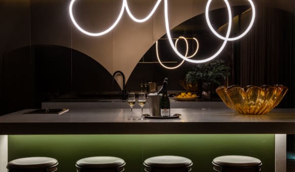 a bar with white stools and a row of lights above it