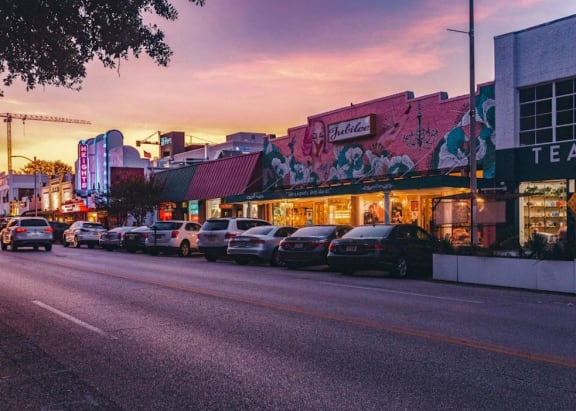 a city street at sunset with cars parked on the road