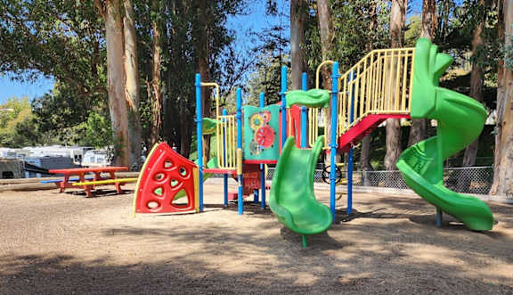 A playground with a green slide and a red and yellow climbing structure at Salinas Sunset Apartments, Salinas, CA, 93907