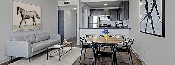 A living room at The Canvas Apartments Nashville with a grey couch and a painting of a horse on the wall.
