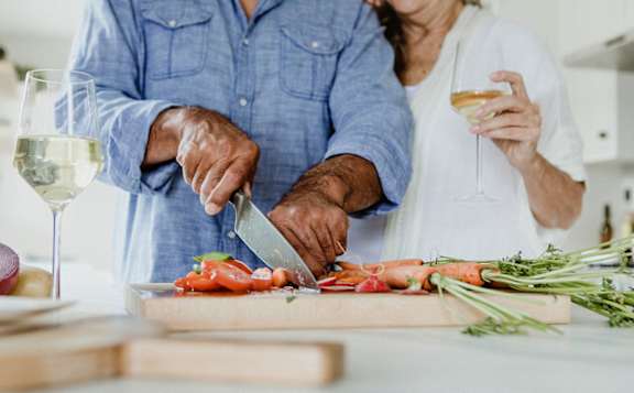 A man and woman are preparing food together in the kitchen.