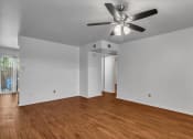 Thumbnail 2 of 9 - an empty living room with wood floors and a ceiling fan