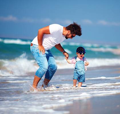 a man and a baby walking in the water on the beach at Hibiscus Pointe, Miami Florida