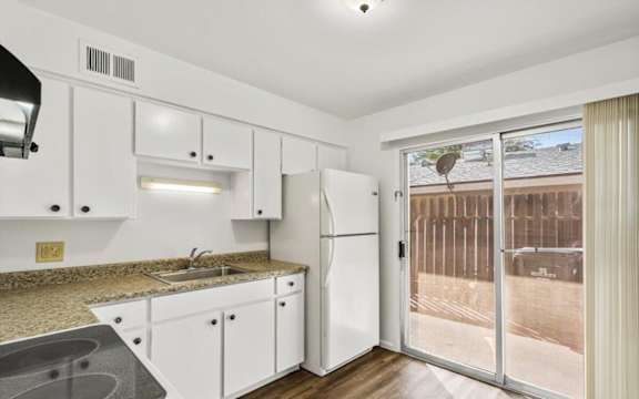 a kitchen with white cabinets and a sliding glass door