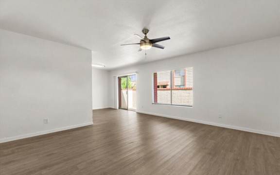 an empty living room with a ceiling fan and a window