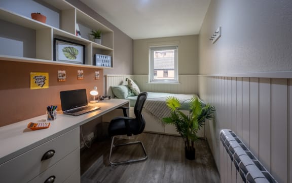 a small bedroom with a desk and a bed