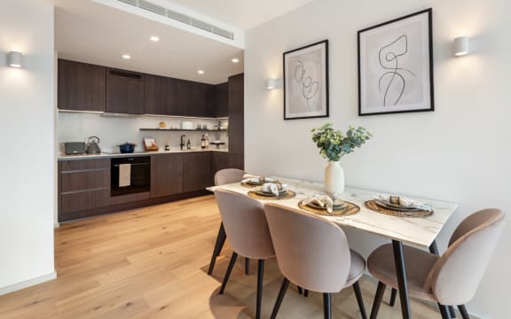 a dining area with a table and chairs and a kitchen in the background