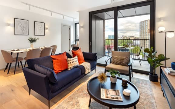a living room with a blue couch and a large glass door leading to a balcony