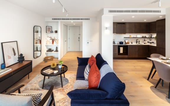a living area with a couch coffee table and a kitchen in the background