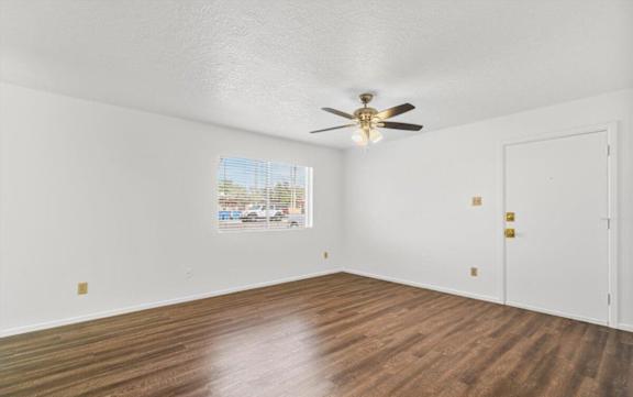 an empty living room with white walls and a ceiling fan
