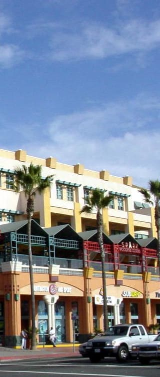 a city street with palm trees and a beach in the background