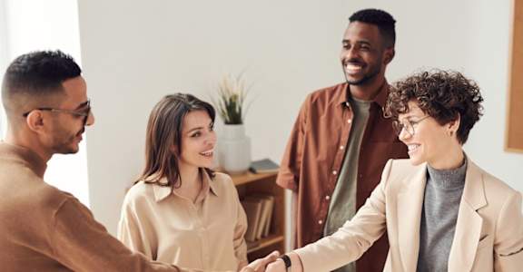 Manager shaking hands with smiling man and man and woman behind them