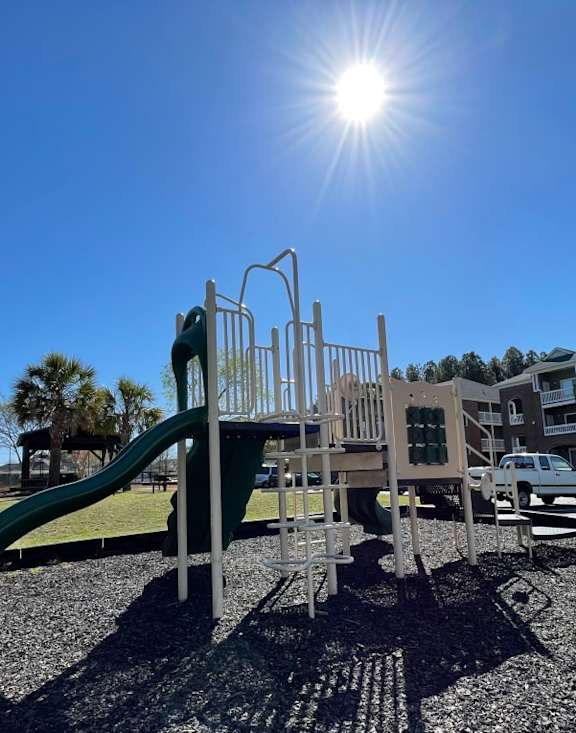 A playground with a green slide and a metal structure.
