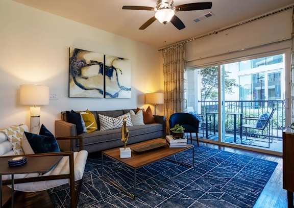 A living room with a grey couch, a wooden coffee table, and a painting on the wall.