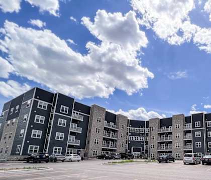 A large apartment complex with multiple buildings and cars parked in the lot.