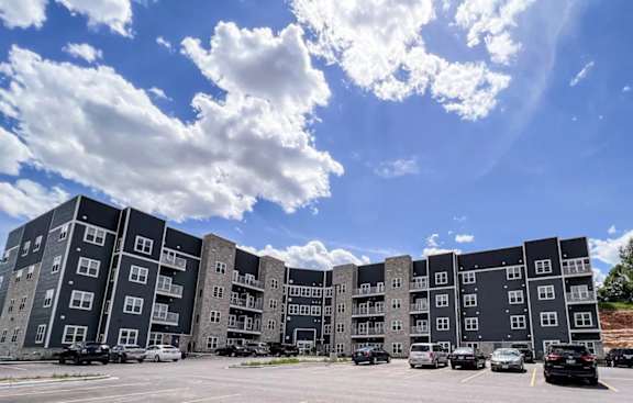 A large apartment complex with multiple buildings and cars parked in the lot.
