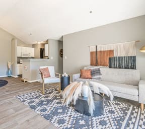 a living area with a couch coffee table and a kitchen in the background