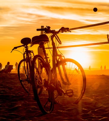 Lifestyle photo of volleyball and bikes on the beach at sunset