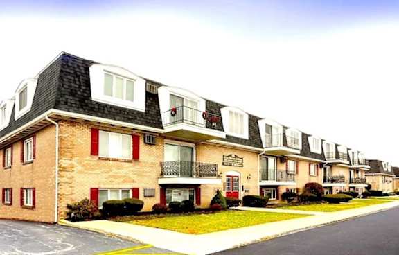 A row of townhouses with balconies and red shutters.