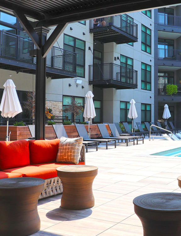a pool area with couches and tables in front of an apartment building at Wildhorse Apartments, Chesterfield, 63017