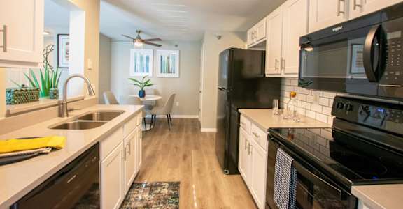 A modern kitchen with black appliances and white cabinets.