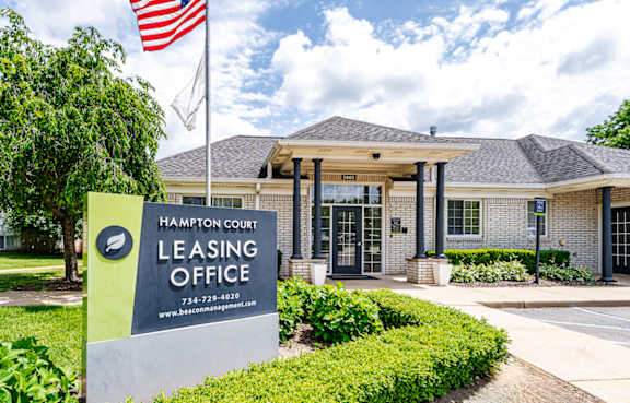 A sign for the Hampton Court Leasing Office stands in front of a building.