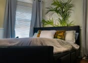 Thumbnail 4 of 29 - Brookmore one bedroom apartment in Pasadena CA with luxury bedding, a dark leather headboard, and six visible pillows on a bed situated diagonally
