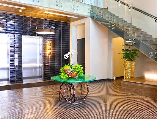 A glass table with a plant on it in a room with a staircase. at The Elle on Lockwood Apartments, Webster Groves, MO, 63119