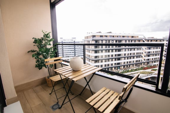 a small balcony with a table and chairs and a large window