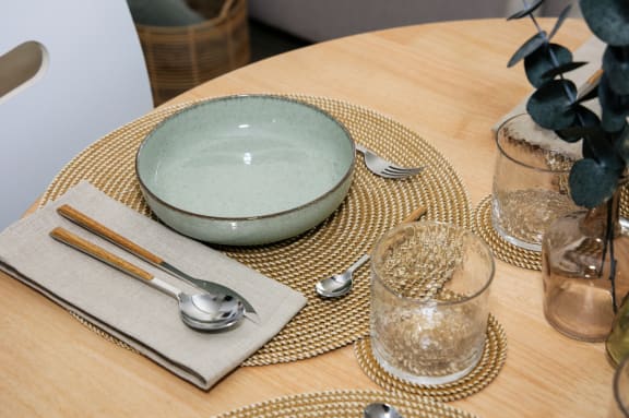 a wooden table with a plate and utensils on top of a table cloth