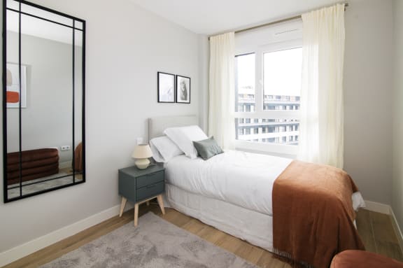 a bedroom with a bed and a large mirror