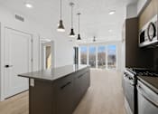 Thumbnail 33 of 51 - A modern kitchen with a large island and stainless steel appliances at Brickside Heights, Millcreek, UT