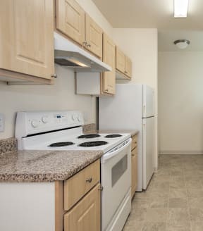 Stanford Heights vacant apartment kitchen with wooden cabinets and white appliances