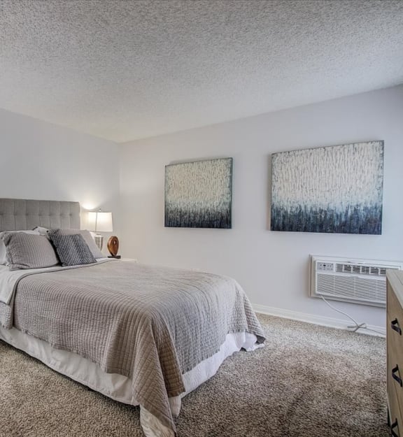 a bedroom with a bed and two paintings on the wall