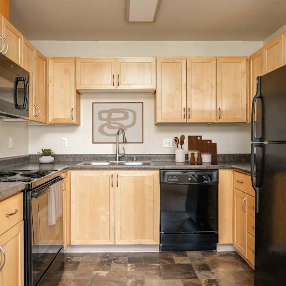 A kitchen with black appliances and wooden cabinets.
