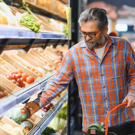  A man in a plaid shirt is shopping for produce in a grocery store.