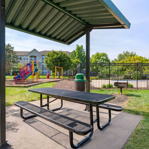 a picnic table in a park with a playground