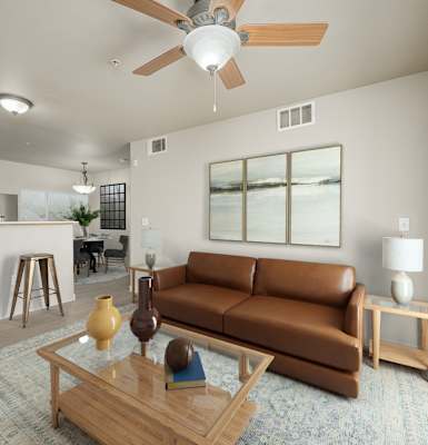 A living room with a brown couch, a ceiling fan, and a coffee table at VISTA CREEK Apartments, Nevada