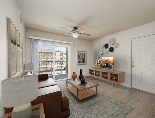 A living room with a brown couch, a wooden coffee table, and a ceiling fan at VISTA CREEK Apartments, Laughlin, NV 89029
