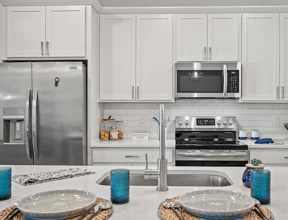 A modern kitchen with a stainless steel refrigerator, microwave, and oven.