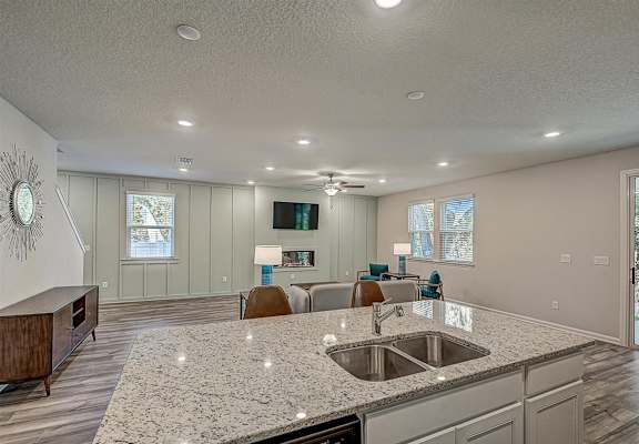 a kitchen with an island and a living room in the background