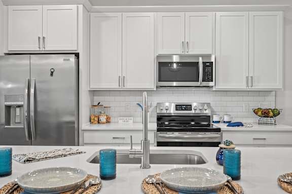 A modern kitchen with a stainless steel refrigerator, microwave, and oven.