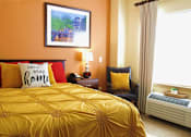 Thumbnail 8 of 8 - A bedroom with a bed, nightstand, chair, and window.