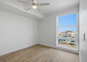 Thumbnail 5 of 51 - Empty room with a window overlooking a parking lot at Brickside Heights, Millcreek, Utah