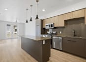 Thumbnail 50 of 51 - A modern kitchen with a dark brown island and stainless steel appliances at Brickside Heights, Millcreek, UT, 84106