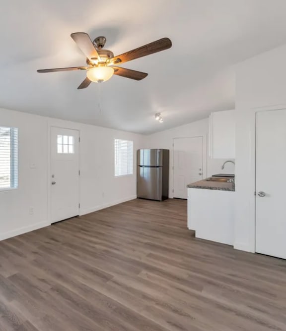 A room with a ceiling fan and wooden flooring.