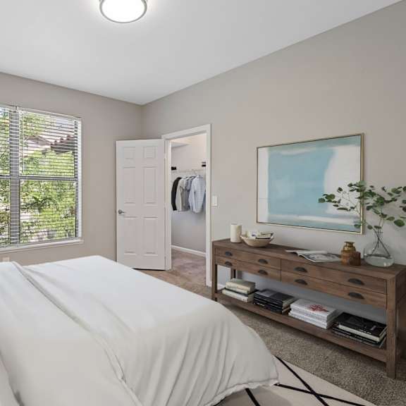 A bedroom with a large bed and a window with blinds.